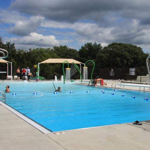 A blue pool with diving boards and concrete framing